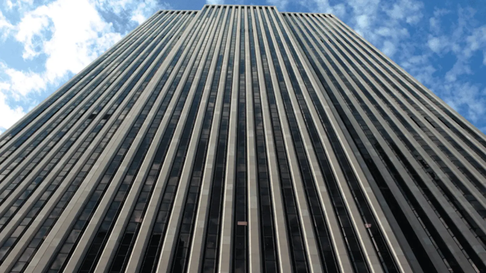 Upward view of the General Motors Building facade in Manhattan against a blue sky