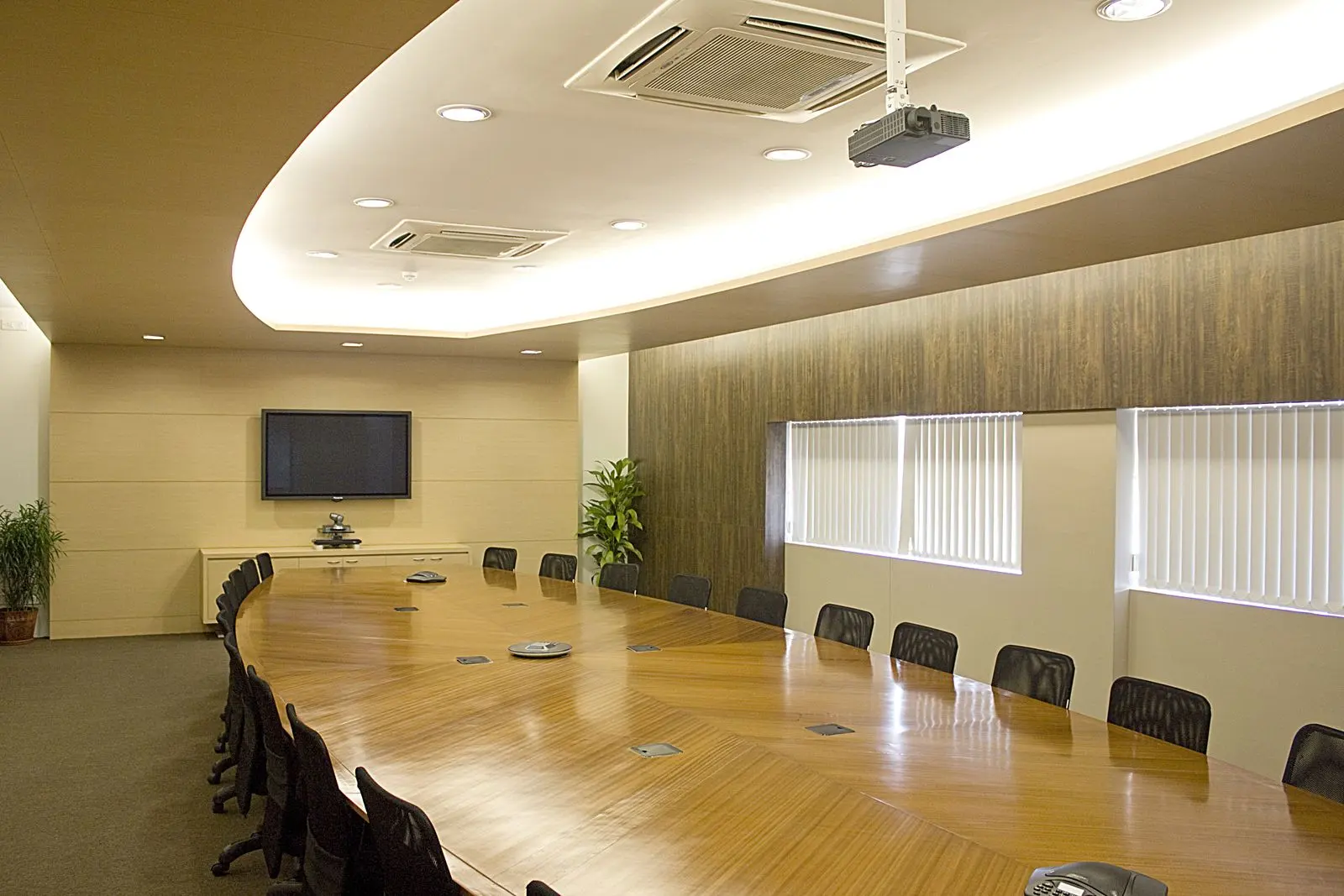 Large boardroom with a long wooden table and a single wall display at the far end