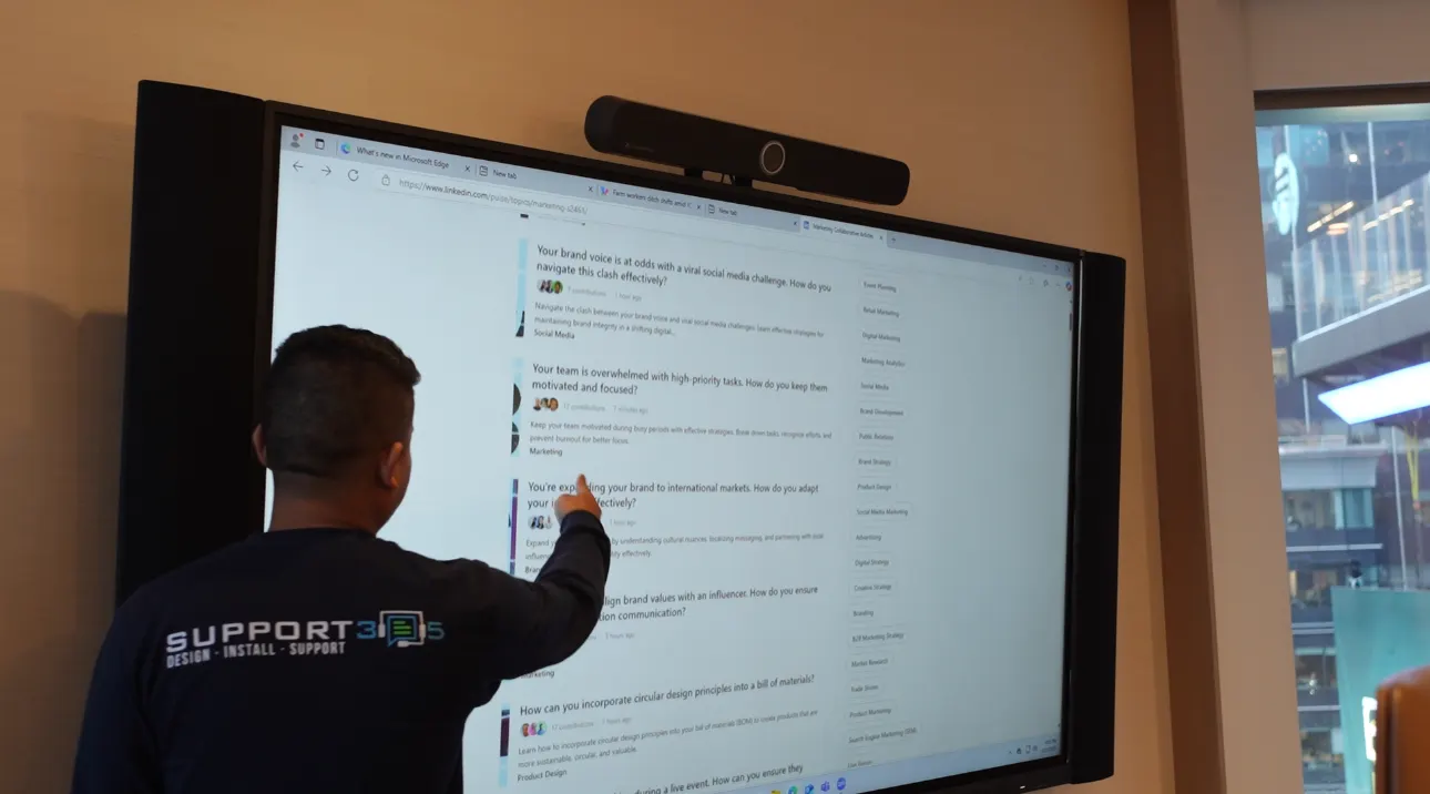 Technician configuring a wall-mounted touch display in a meeting room
